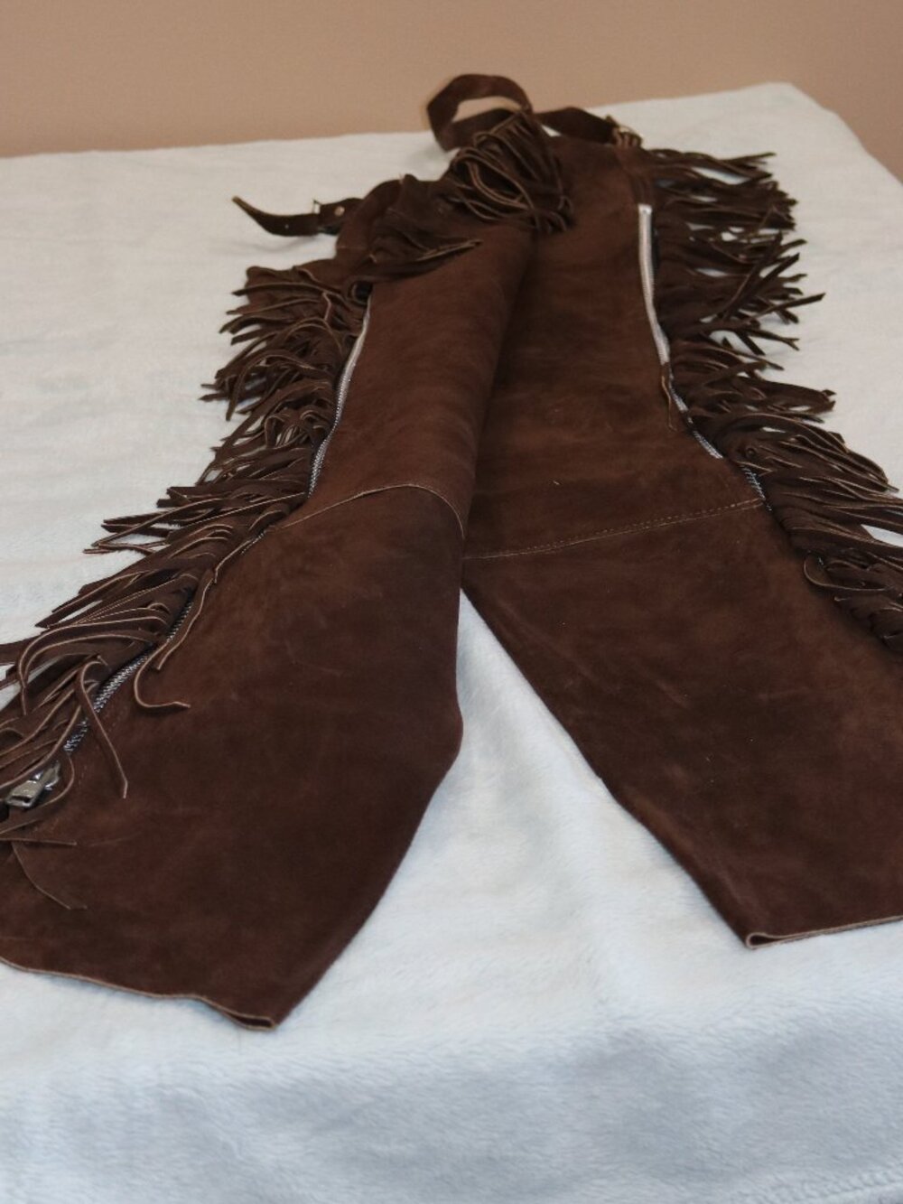 Brown leather chaps with fringe and silver zippers.
